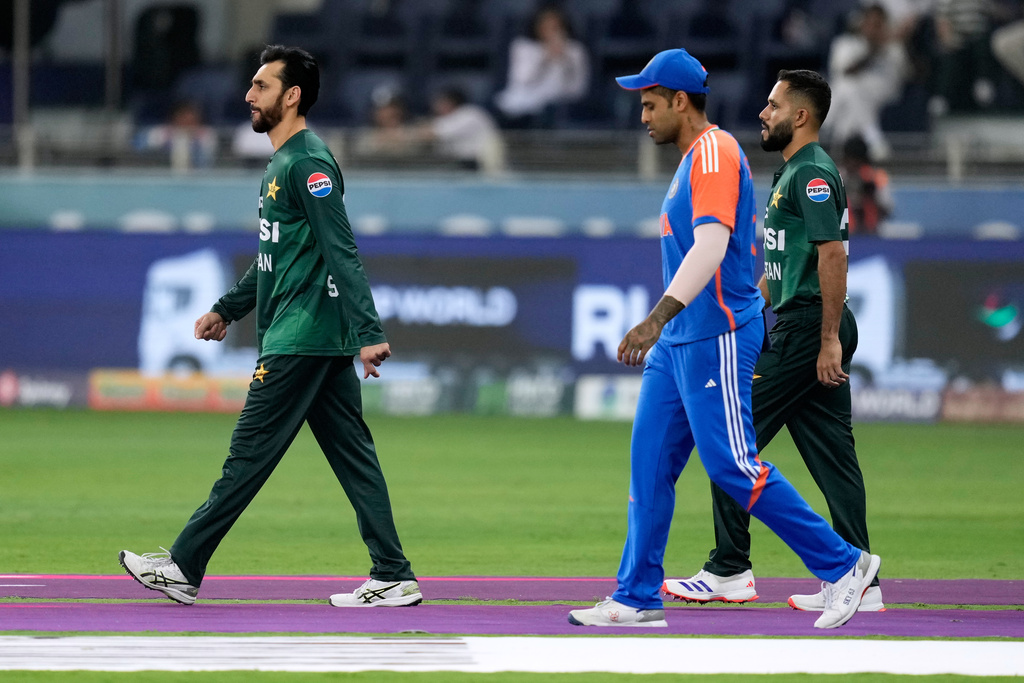 Pakistan's captain Salman Agha, left, and India's captain Suryakumar Yadav, center, walk out on to the field for the national anthems before the Asia Cup cricket final between India and Pakistan at Dubai International Cricket Stadium, United Arab Emirates, Sunday, Sept. 28, 2025. (AP Photo/Altaf Qadri)
