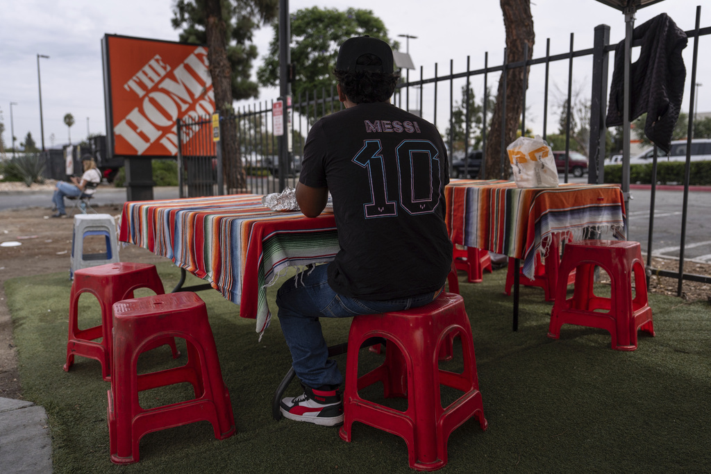 A day laborer eats his meal near a Home Depot sign in the Van Nuys section of Los Angeles, Thursday, Aug. 28, 2025. (AP Photo/Jae C. Hong)