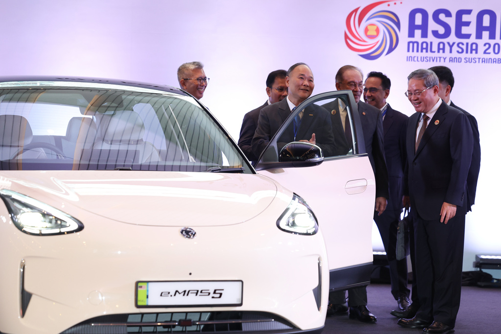 Chinese Premier Li Qiang, right, reacts as he, along with Malaysian Prime Minister Anwar Ibrahim, center, inspects a car produced by Malaysia's national automaker, Proton, in which China's Zhejiang Geely Holding Group holds a 49.9% stake, ahead of the signing ceremony for the ASEAN–China Free Trade Area 3.0 Upgrade and the ASEAN–China summit, held as part of the ASEAN summit in Kuala Lumpur, Malaysia Tuesday, Oct. 28, 2025. (Chalinee Thirasupa/Pool Photo via AP)