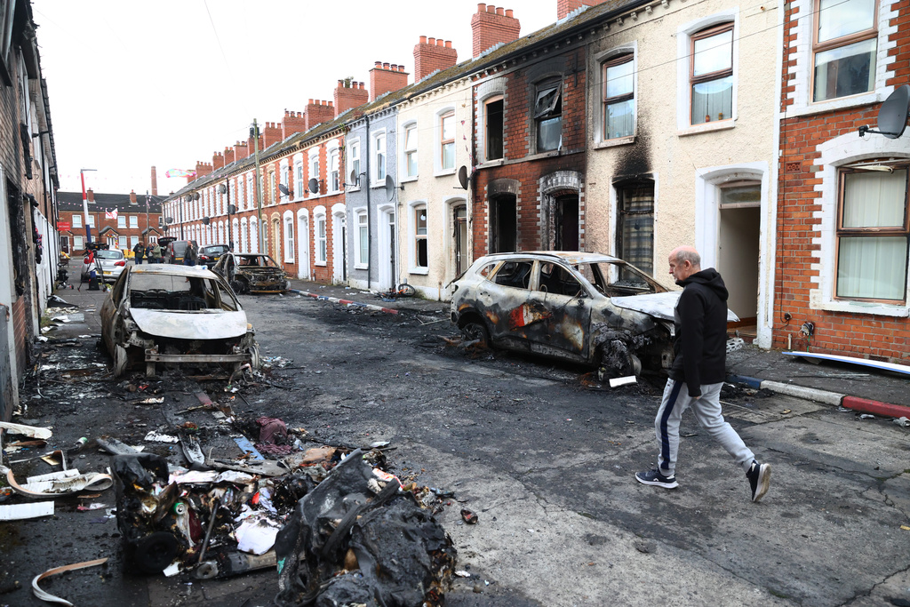 A man walks down a street after rioting broke out late Tuesday, in east Belfast, Northern Ireland, Wednesday, June 10, 2026, following a stabbing incident. (AP Photo/Peter Morrison)