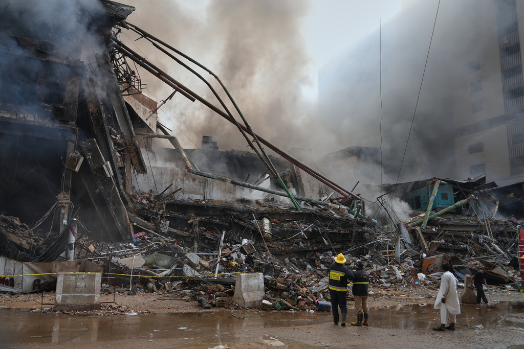 Firefighters examine a collapsed portion of a multi-story shopping mall following a massive fire that broke out overnight, in Karachi, Pakistan, Sunday, Jan. 18, 2026. (AP Photo/Mohammad Farooq)