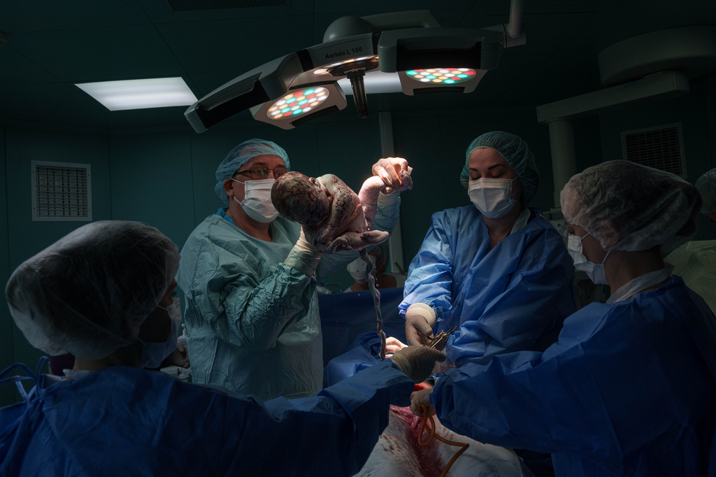 A doctor holds a newborn girl, Diana, after performing a cesarean section on her mother, Olha Karpenko, at the regional perinatal center of Zaporizhzhia, Ukraine, Wednesday, May 6, 2026. (AP Photo/Evgeniy Maloletka)