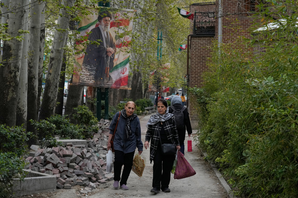 Women walk past a banner depicting the late Iranian Supreme Leader Ayatollah Ali Khamenei, who was killed in the U.S. and Israel strikes on Feb. 28, in northern Tehran, Iran, Sunday, April 12, 2026. (AP Photo/Vahid Salemi)