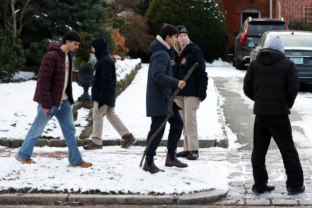 Pedestrians ask FBI agents, on the sidewalk on Cooke St. for updates, in Providence, R.I., two days after a shooting occurred on Brown University's campus, Monday, Dec. 15, 2025. (Lily Speredelozzi/The Sun Chronicle via AP)