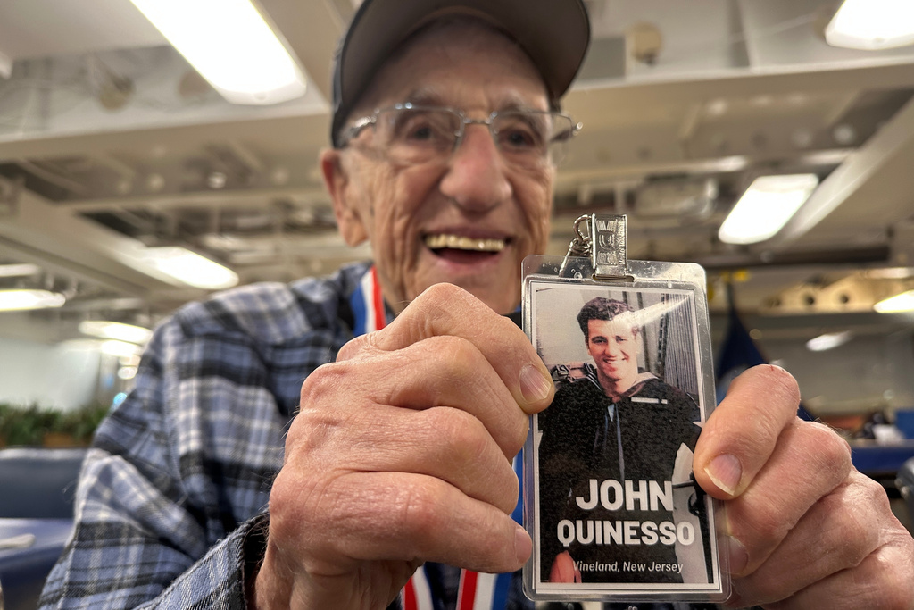 John "Johnny Q" Quinesso Sr, a WWII veteran, holds a photo of his younger self during his 100th birthday celebration on Thursday, Feb. 5, 2026 in Camden, N.J., aboard the Battleship New Jersey. (AP Photo/Tassanee Vejpongsa)