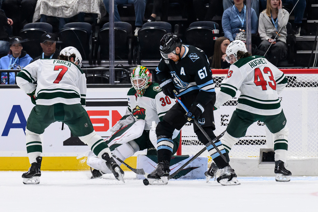 Utah Mammoth left wing Lawson Crouse (67), Minnesota Wild defender Brock Faber (7), Wild defender Quinn Hughes (43) and Wild goaltender Jesper Wallstedt (30) battle for the puck in front of the net during the second period of an NHL hockey game, Friday, Feb. 27, 2026, in Salt Lake City. (AP Photo/Tyler Tate)