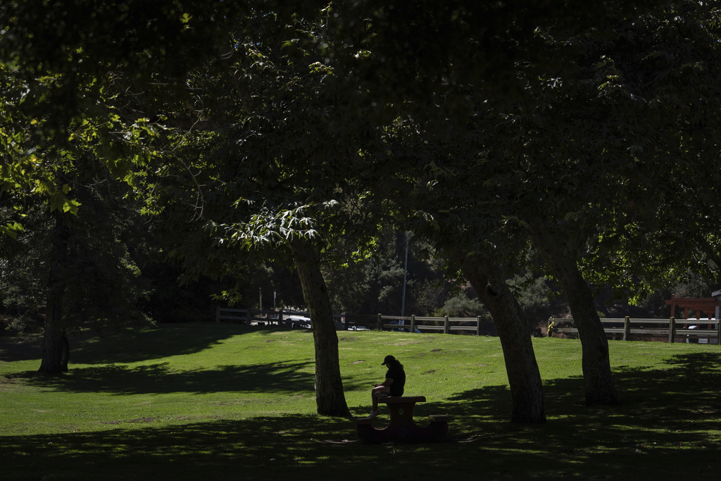A woman rests on a picnic table at Griffith Park in Los Angeles, Tuesday, Aug. 19, 2025. (AP Photo/Jae C. Hong)