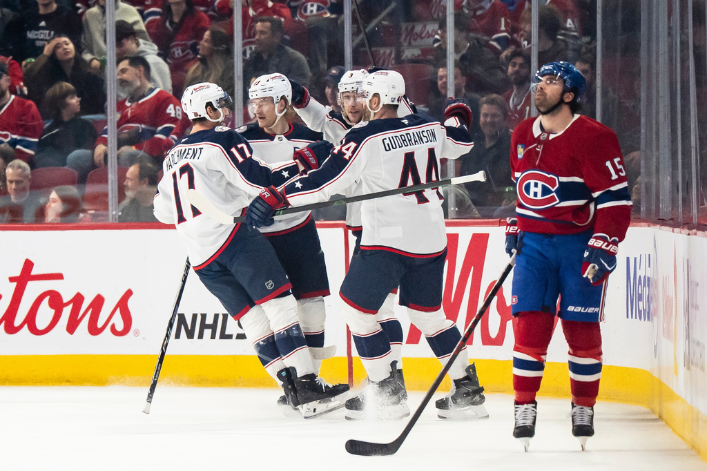 Columbus Blue Jackets' Mason Marchment (17), Danton Heinen, second from left, Erik Gudbranson (44) and Charlie Coyle (3) celebrate after a goal while Montreal Canadiens' Alex Newhook (15) looks on during first-period NHL hockey game action in Montreal, Saturday, April 11, 2026. (Christopher Katsarov/The Canadian Press via AP)