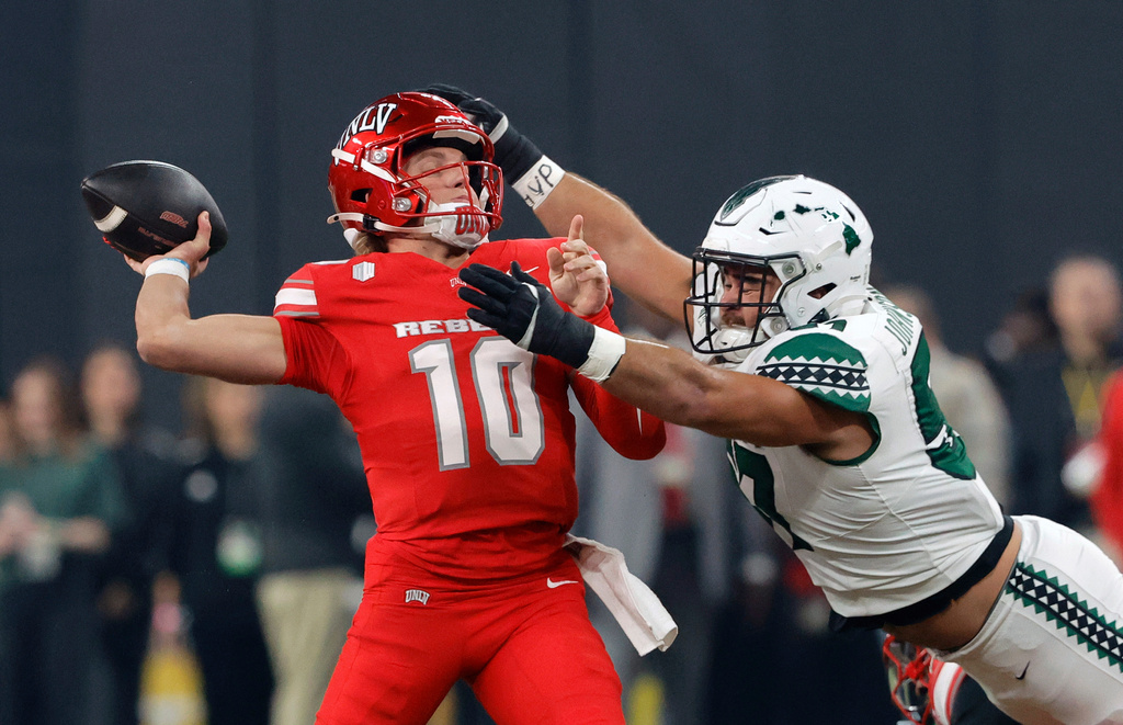 UNLV quarterback Anthony Colandrea (10) passes under pressure from Hawaii defensive lineman Jackie Johnson III (57) during the first half of an NCAA college football game Friday, Nov. 21, 2025, in Las Vegas. (Steve Marcus/Las Vegas Sun via AP)