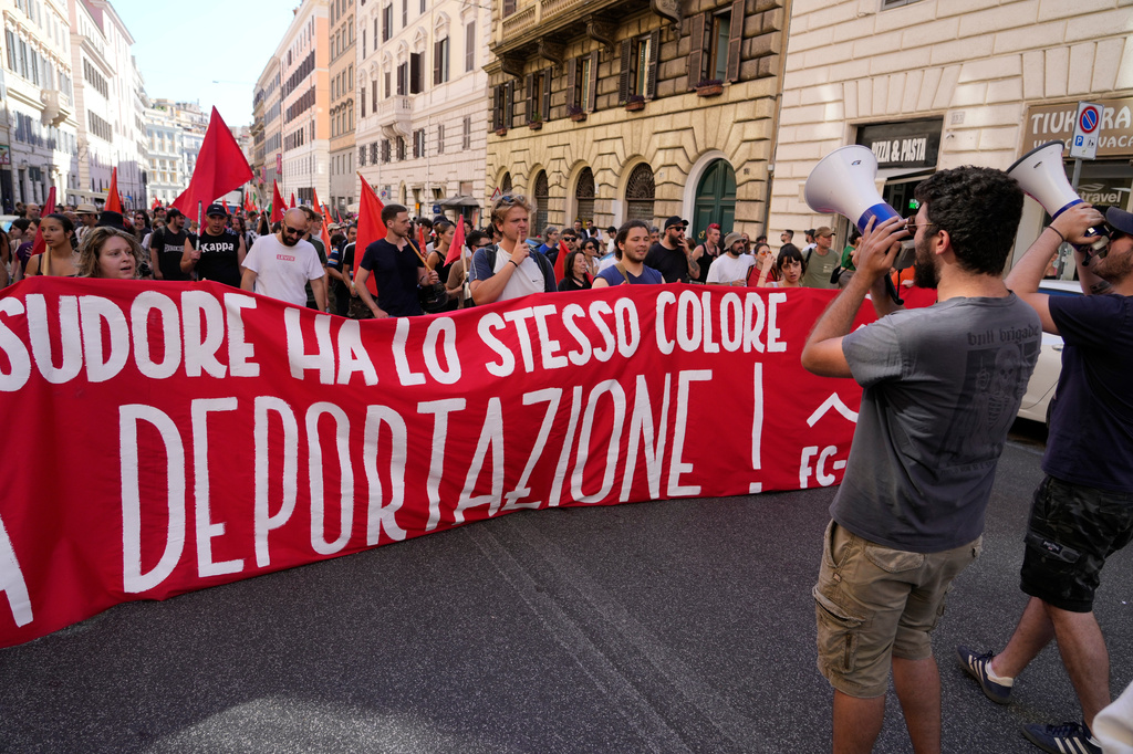 People hold a banner in Italian reading "Skin and sweat have the same color, no deportation' during a march in Rome, Saturday, June 13, 2026, to protest Italy's security and migration package, including a migrant "repatriation bonus" scheme criticized by opposition parties and legal groups as unconstitutional and ethically problematic. (AP Photo/Gregorio Borgia)