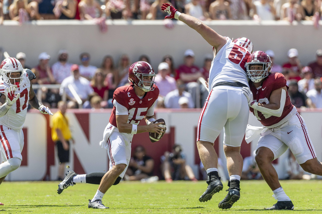Alabama quarterback Ty Simpson (15) works to find a running lane with offensive lineman Parker Brailsford (72) protecting against Wisconsin defensive lineman Ben Barten (68) during the first half of an NCAA college football game, Saturday, Sept. 13, 2025, in Tuscaloosa, Ala. (AP Photo/Vasha Hunt)