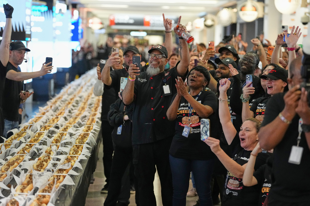 Volunteers cheer as the results of their Guinness World Record was announced on National Cheesesteak Day at Philadelphia International Airport, Tuesday, March 24, 2026, in Philadelphia. (AP Photo/Matt Rourke)