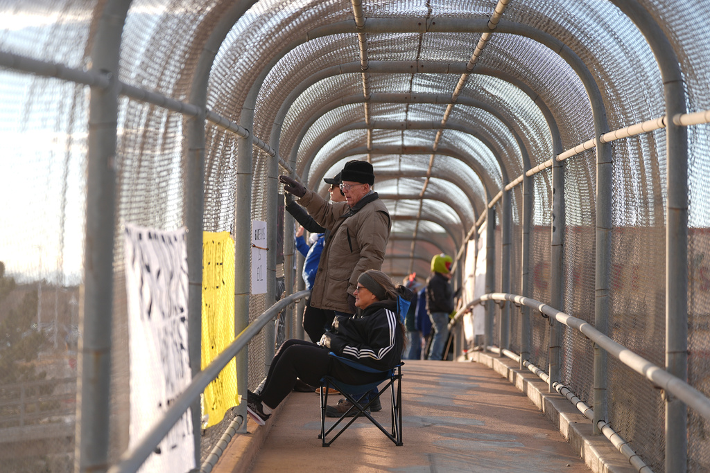 Protesters wave at motorists, Jan. 28, 2026, from an overpass along Interstate 25 in Northglenn, Colo. (AP Photo/David Zalubowski)