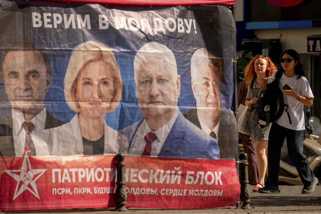 Women walk next to a campaign tent of the Patriotic Electoral Bloc with the slogan "We believe in Moldova" in Chisinau, Moldova, Tuesday, Sept. 23, 2025, ahead of parliamentary elections taking place on Sept. 28. (AP Photo/Vadim Ghirda)