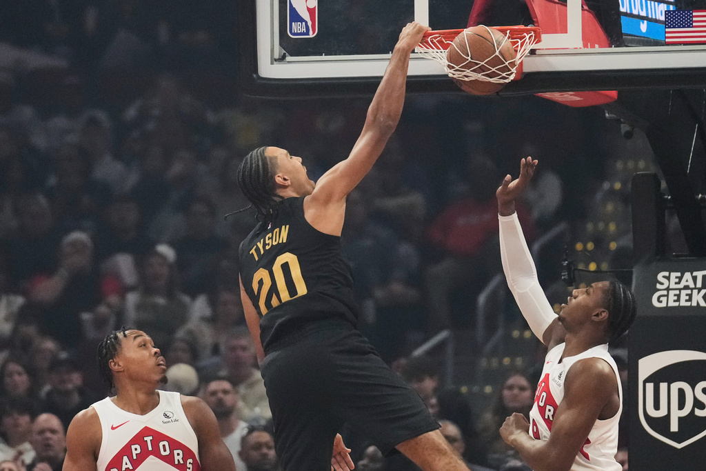 Cleveland Cavaliers' Jaylon Tyson (20) dunks between Toronto Raptors' Scottie Barnes, left, and RJ Barrett, right, in the first half of an an NBA Cup basketball game in Cleveland, Friday, Oct. 31, 2025. (AP Photo/Sue Ogrocki)