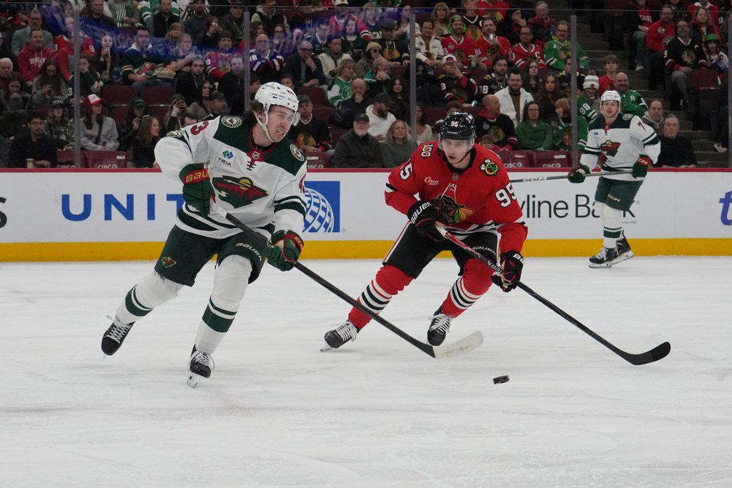 Minnesota Wild defenseman Quinn Hughes, left, and Chicago Blackhawks wing Ilya Mikheyev (95) go for the puck during the first period of an NHL hockey game, Tuesday, March, 17, 2026, in Chicago. (AP Photo/David Banks)