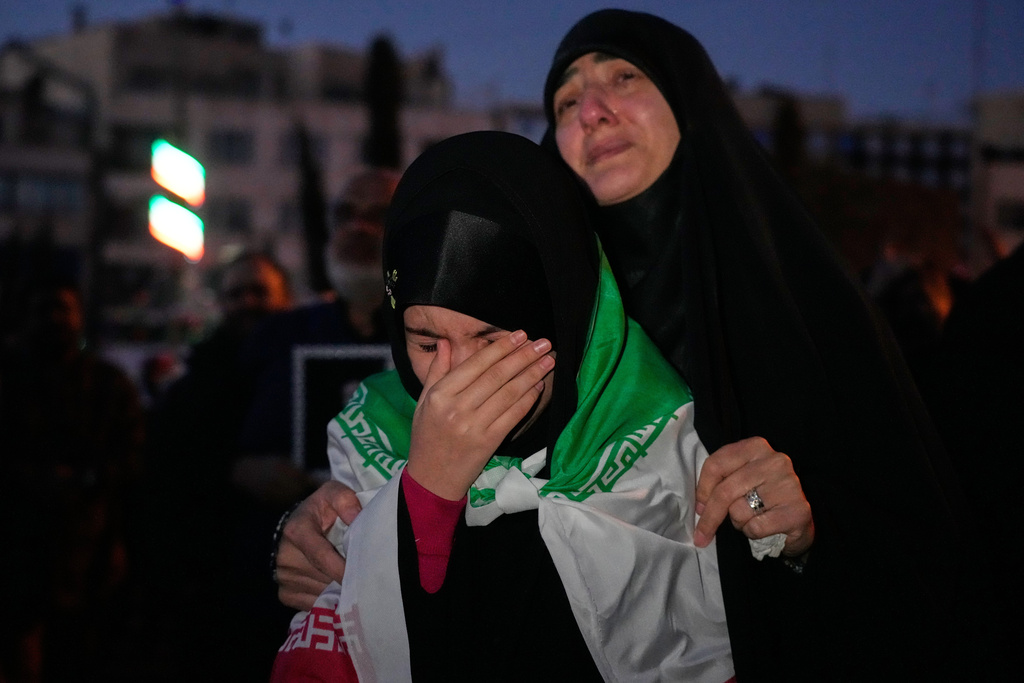 Government supporters mourn in a gathering after state TV officially announced the death of Iranian Supreme Leader Ayatollah Ali Khamenei, as one of them wears an Iranian flag, in Tehran, Iran, Sunday, March 1, 2026. (AP Photo/Vahid Salemi)
