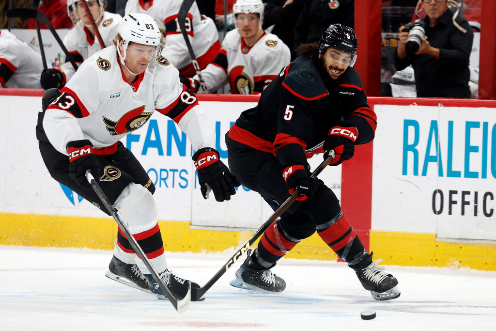 Carolina Hurricanes' Jalen Chatfield (5) battles Ottawa Senators' Stephen Halliday (83) for the puck during the first period of an NHL hockey game in Raleigh, N.C., Tuesday, Feb. 3, 2026. (AP Photo/Karl DeBlaker)