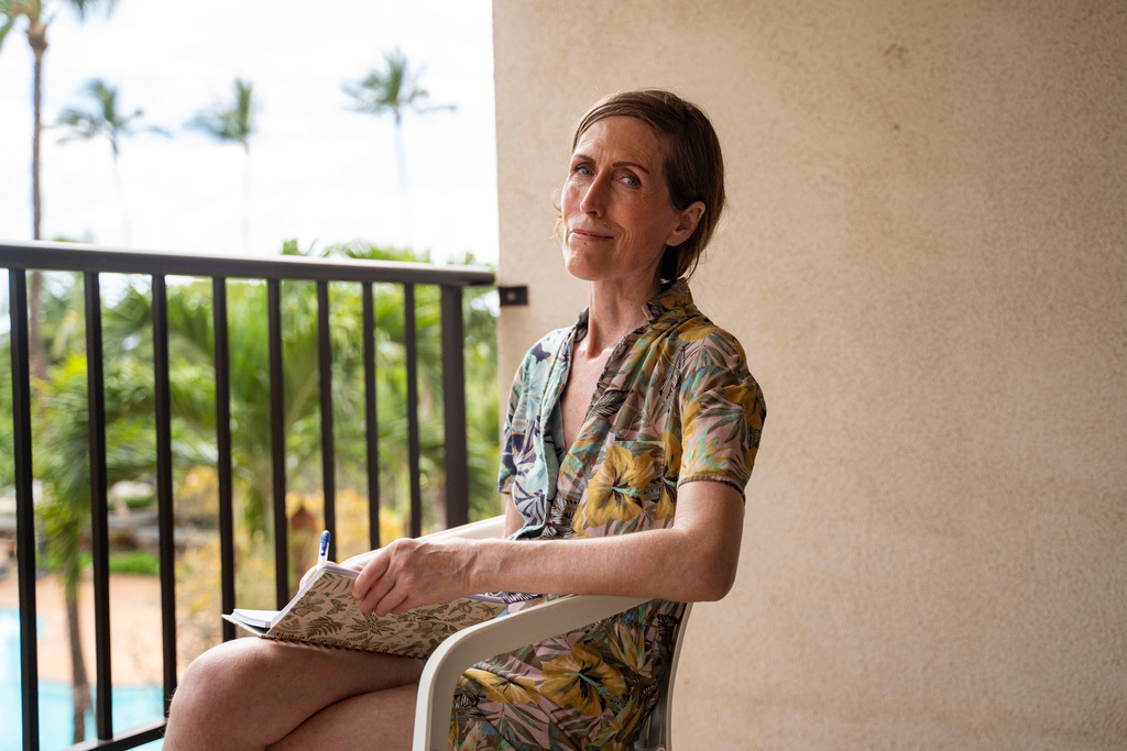 Mari Younger poses for a portrait on the balcony of her converted hotel room where she lives after being displaced by the Maui fires two years prior, in Kihei, Hawaii, Wednesday, March 4, 2026. (AP Photo/Mengshin Lin)