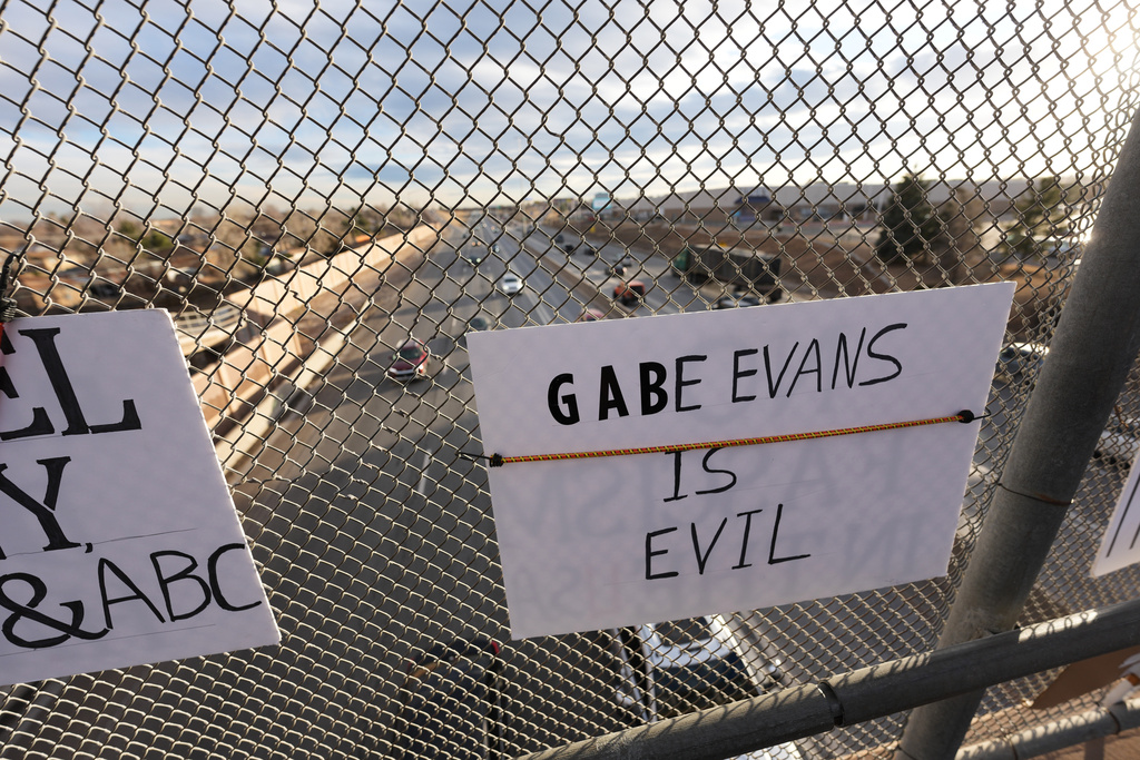 A sign against Rep. Gabe Evans, R-Colo, hangs from a fence Wednesday, Jan. 28, 2026, from an overpass along Interstate 25 in Northglenn, Colo. (AP Photo/David Zalubowski)