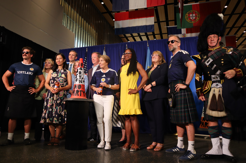 Boston Mayor Michelle Wu, center left, Massachusetts Gov. Maura Healey, center right, Scottish football fans and others pose with the commemorative Boston Cone during a welcoming ceremony at Boston Logan International Airport, Tuesday, July 14, 2026, in Boston. (AP Photo/Leah Willingham)