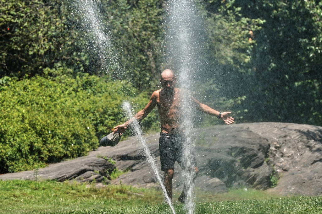 A man takes advantage of a sprinkler during hot weather in New York's Central Park, Thursday, July 2, 2026. (AP Photo/Richard Drew)