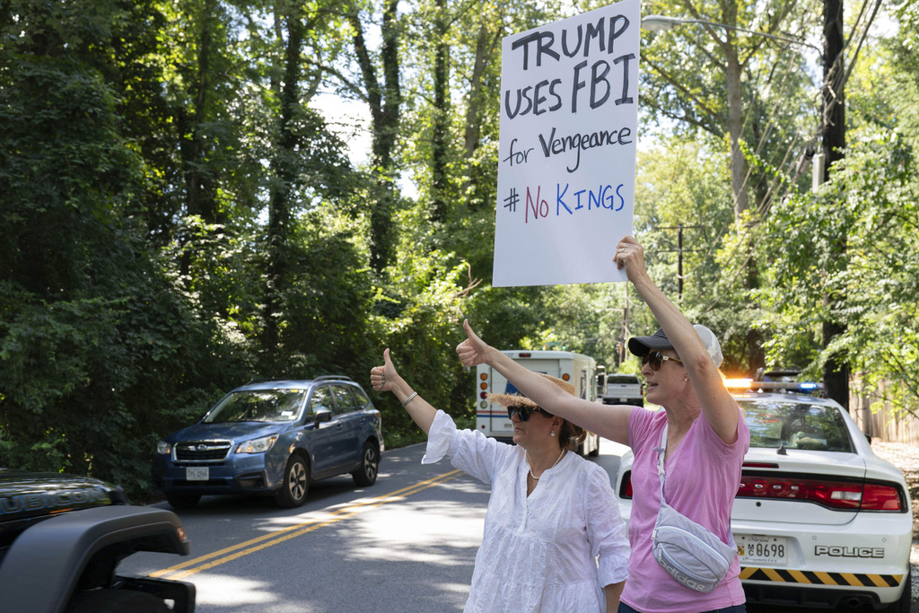 Neighbors give thumbs-up to cars passing by John Bolton's home as FBI agents search the house in Bethesda Md, Friday, August. 22, 2025. (AP Photo/Jose Luis Magana)