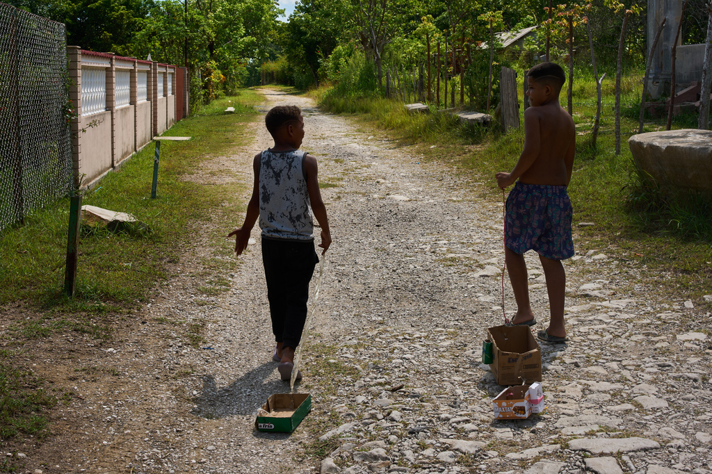 Children drag toys made from cardboard boxes as they walk in Minas, in Cuba's Havana province, Monday, Aug. 31, 2026. (AP Photo/Ramon Espinosa)