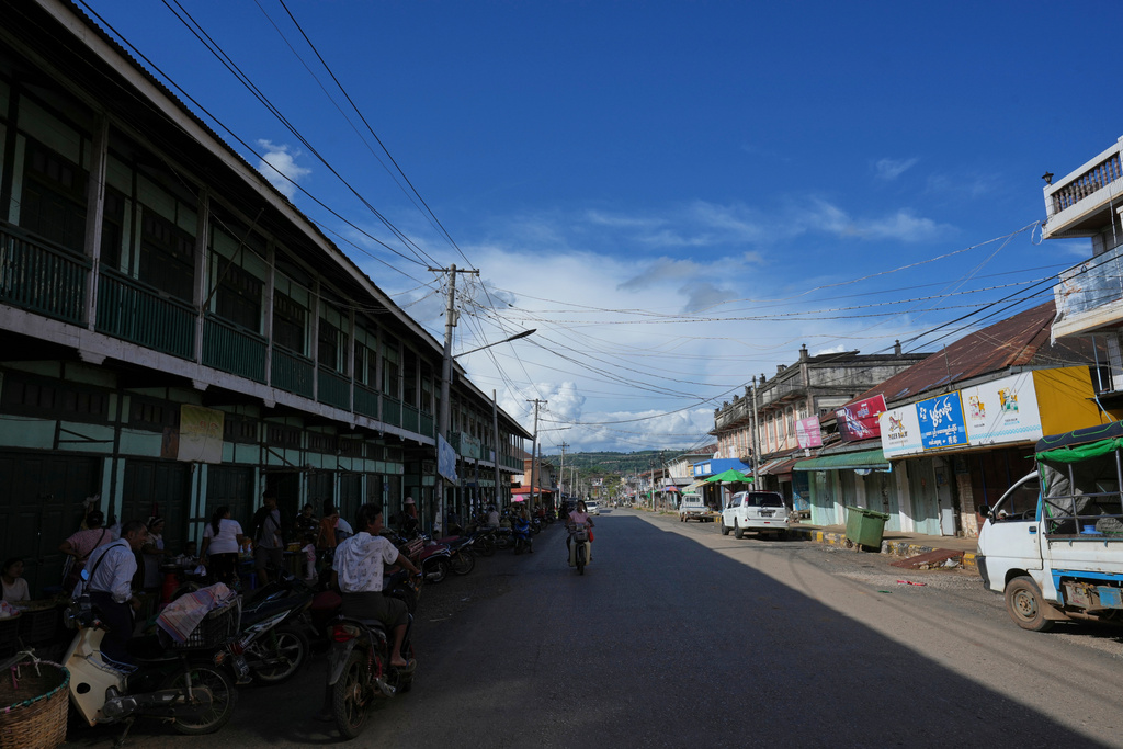 In this photo taken during a trip supervised by pro-military Myanmar media, locals ride motorbikes past a street in Kyaukme, northern Shan State, Myanmar, Friday, Oct.10, 2025. (AP Photo/Aung Shine Oo)