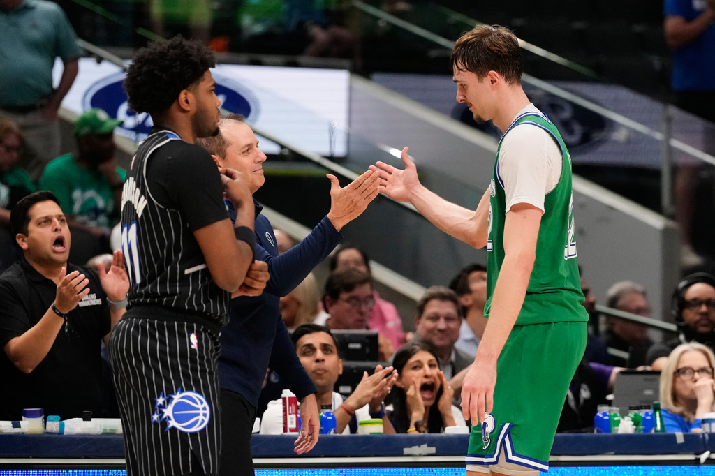 Dallas Mavericks forward Cooper Flagg, right, is greeted at the bench by assistant coach Frank Vogel, center left, as Orlando Magic's Jase Richardson, left, stands by in the second half of an NBA basketball game Friday, April 3, 2026, in Dallas. (AP Photo/Tony Gutierrez)