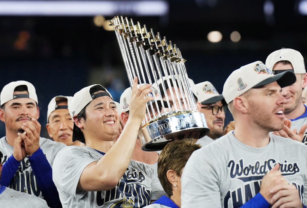 Los Angeles Dodgers pitcher Shohei Ohtani, left, lifts the trophy as the Dodgers celebrate after defeating the Toronto Blue Jays in Game 7 of baseball's World Series, Sunday, Nov. 2, 2025, in Toronto. (Nathan Denette/The Canadian Press via AP)
