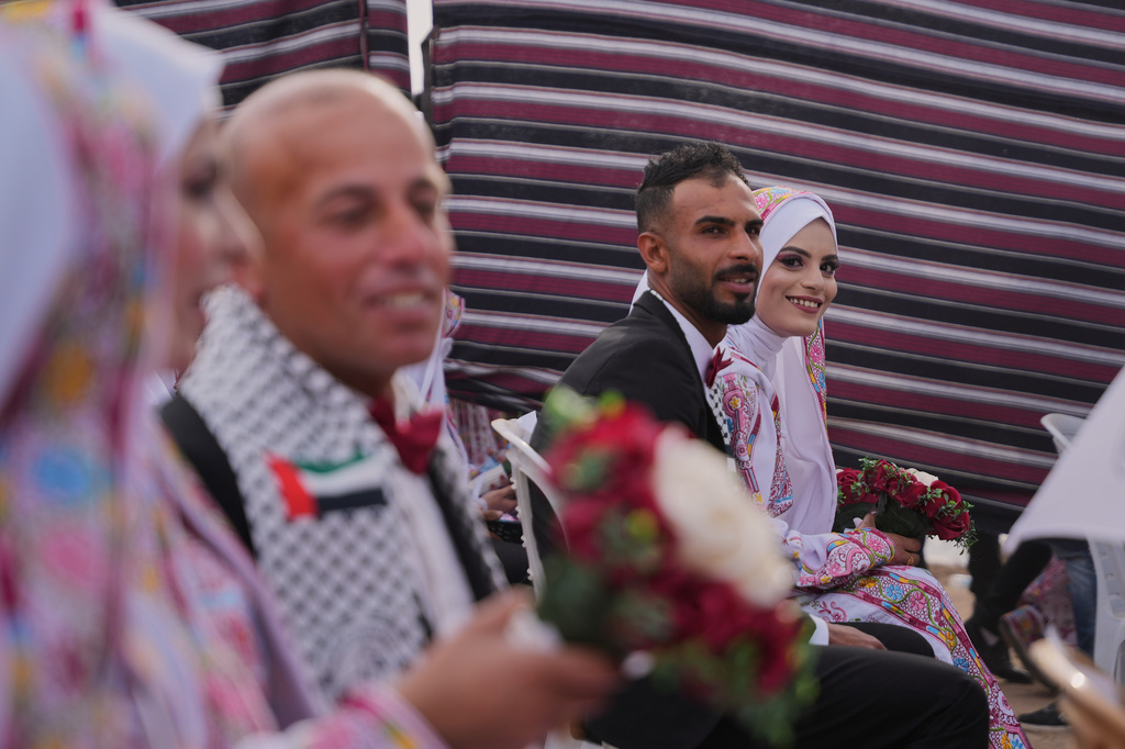 Palestinian bride Ola Al-Sharif looks at the camera as she participates with her groom, Mohamed al-sharif, in a mass wedding ceremony in Deir al-Balah, central Gaza Strip, Friday, April 24, 2026. (AP Photo/Abdel Kareem Hana)