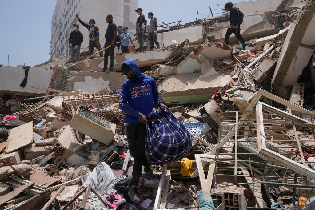 A man retrieves items from the rubble two days after earthquakes struck La Guaira, Venezuela, Friday, June 26, 2026. (AP Photo/Ariana Cubillos)