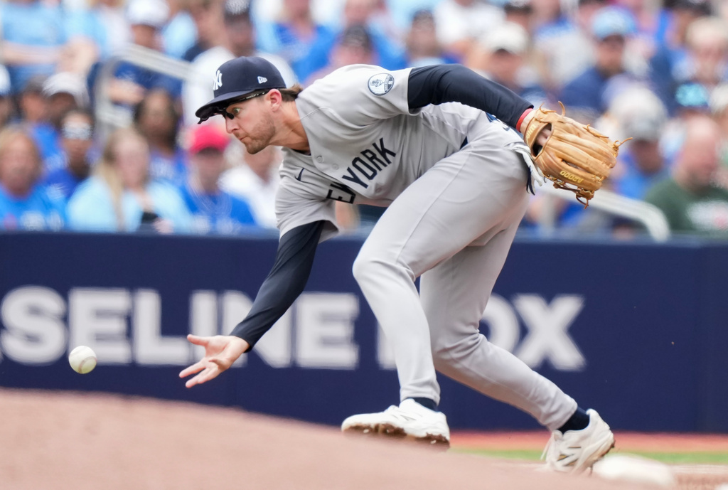 New York Yankees third baseman Ryan McMahon barehands the ball before throwing it to first base but Toronto Blue Jays' Charles McAdoo was safe during the fourth inning of a baseball game in Toronto, Sunday, Aug. 16, 2026. (Nathan Denette/The Canadian Press via AP)