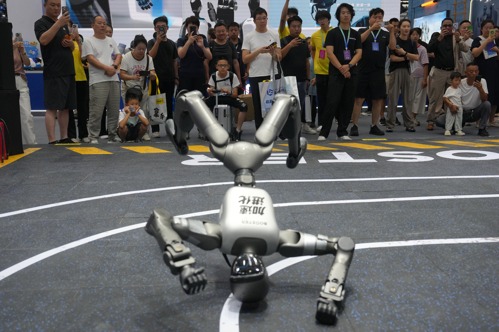 Visitors watch a humanoid robot at a booth during the World Robot Conference at the Beiren Yichuang International Convention and Exhibition Centre in Beijing, Wednesday, Aug. 19, 2026. (AP Photo/Andy Wong)