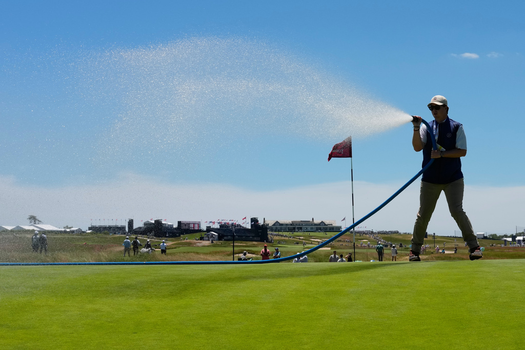 A course worker waters the green on the fifth hole during a practice round for the U.S. Open golf tournament at Shinnecock Hills Golf Club in Southampton, N.Y., Tuesday, June 16, 2026.(AP Photo/David J. Phillip)