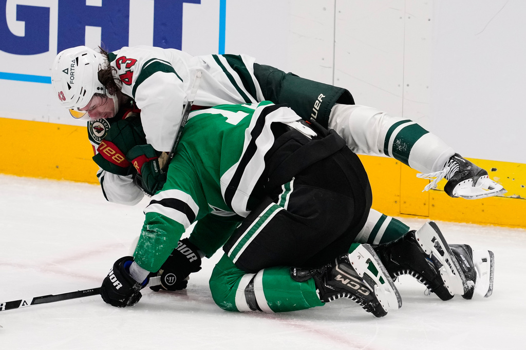 Minnesota Wild defenseman Quinn Hughes, top and Dallas Stars' Adam Erne (73) fight in the third period of an NHL hockey game Thursday, April 9, 2026, in Arlington, Texas. (AP Photo/Tony Gutierrez)