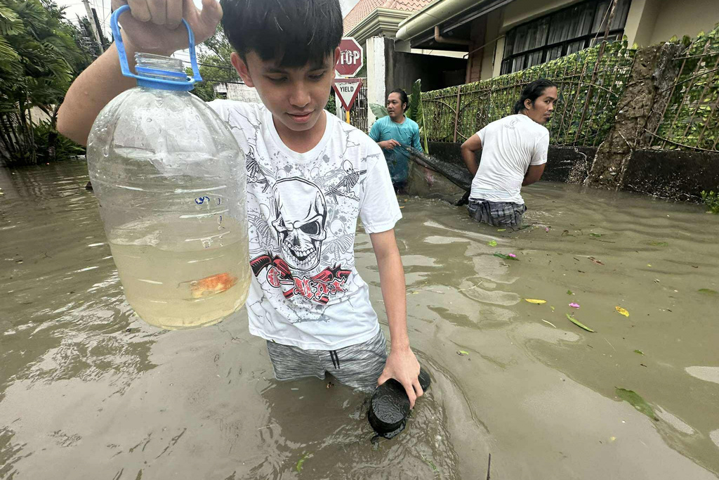 A boy shows a goldfish which they caught after a nearby fish farm overflowed due to floodwaters caused by Typhoon Kalmaegi as it affects Cebu city, central Philippines, Tuesday Nov. 4, 2025. (AP Photo/Jacqueline Hernandez)