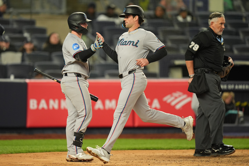 Miami Marlins' Liam Hicks, left, greets Graham Pauley, center, as he scores on a single hit by Xavier Edwards during the eighth inning of a baseball game against the New York Yankees, Sunday, April 5, 2026, in New York. (AP Photo/Seth Wenig)