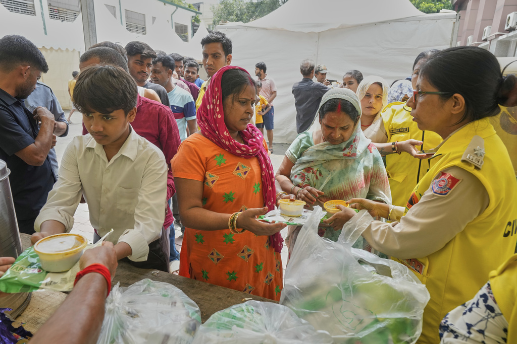 Bindu Pandey, center, takes food in a temporary school shelter, which houses residents displaced from the banks of the Yamuna River by incessant rain in the higher regions in New Delhi, India, Friday, Sept. 5, 2025. (AP Photo/Manish Swarup)