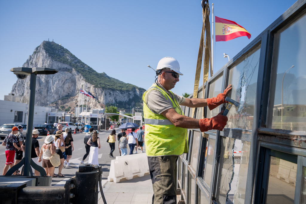 Against the backdrop of the Rock of Gibraltar, workers dismantle a Spanish border checkpoint that separated the disputed British overseas territory from Spain in La Línea de la Concepción, Spain, Monday, July 6, 2026. (AP Photo/Marcos Moreno)