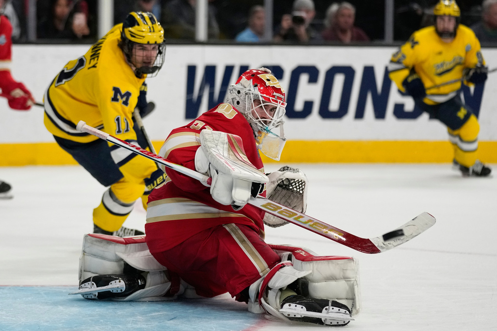 Denver goaltender Johnny Hicks (31) knocks the puck away against Michigan in overtime of a semifinal game in the NCAA Frozen Four men's college hockey tournament Thursday, April 9, 2026, in Las Vegas. (AP Photo/John Locher)