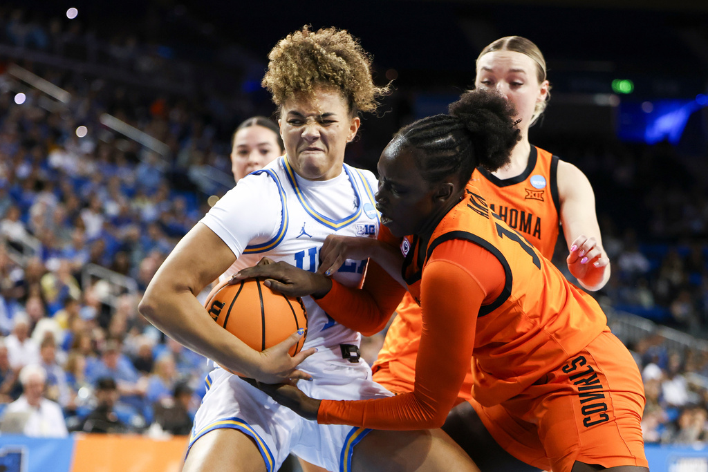UCLA guard Kiki Rice, front left, and Oklahoma State forward Achol Akot, front right, battle for the ball as Oklahoma State guard Amari Whiting, back right, watches during the first half in the second round of the NCAA college basketball tournament, Monday, March 23, 2026, in Los Angeles. (AP Photo/Jessie Alcheh)