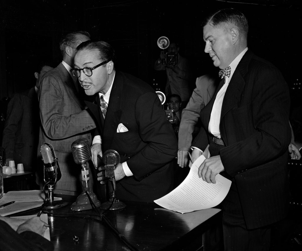 FILE - Dalton Trumbo, left, Hollywood screenwriter, shouts from the witness stand as he tries to make a statement before the House Un-American Activities Committee, Oct. 28, 1947, in Washington. At right is his attorney Robert Kenny. Trumbo was excused from further testimony when he refused to state whether he is or has been a communist. (AP Photo/Byron Rollins, File)