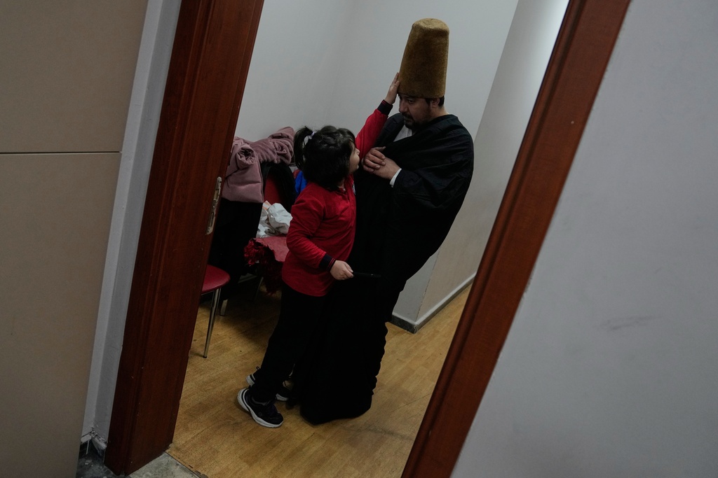 A whirling dervish of the Mevlevi order plays with his daughter before before a Sheb-i Arus ceremony at a municipality cultural center in Istanbul, Turkey, Wednesday, Dec. 17, 2025, to commemorate the death of 13th century Islamic scholar, poet and Sufi mystic Jalaladdin Rumi.(AP Photo/Khalil Hamra)