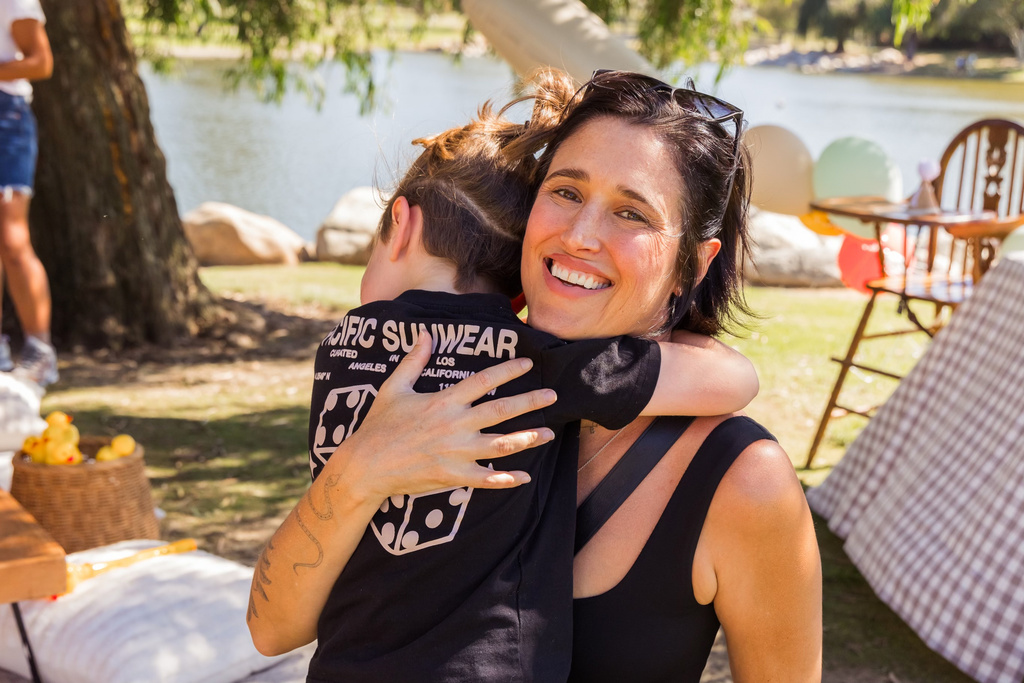 In this photo provided by Ana Fiero, Kelly Sue Milano holds her 6-year-old son, who is on the autism spectrum, at an outdoor party in Irvine, Calif., on Oct. 20, 2025. (Ana Fiero via AP)