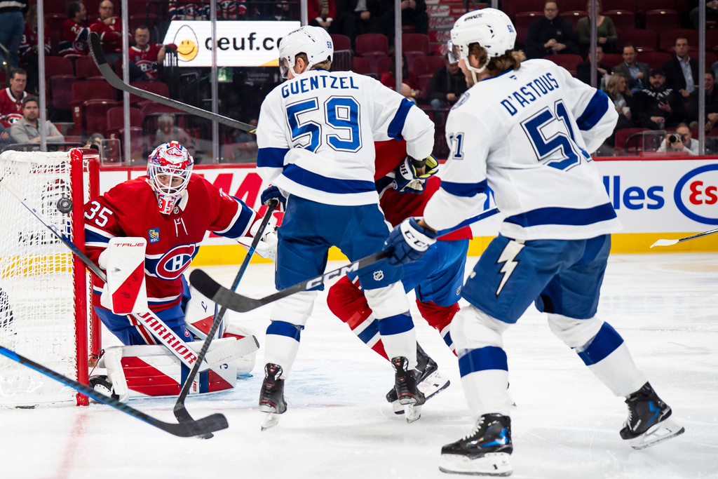 Montreal Canadiens goaltender Sam Montembeault (35) watches the puck go wide of the net as Tampa Bay Lightning' Jake Guentzel (59) and Charle-Edouard D'Astous (51) stand in front during second period NHL hockey action in Montreal on Tuesday, Dec. 9, 2025. (Christopher Katsarov/The Canadian Press via AP)