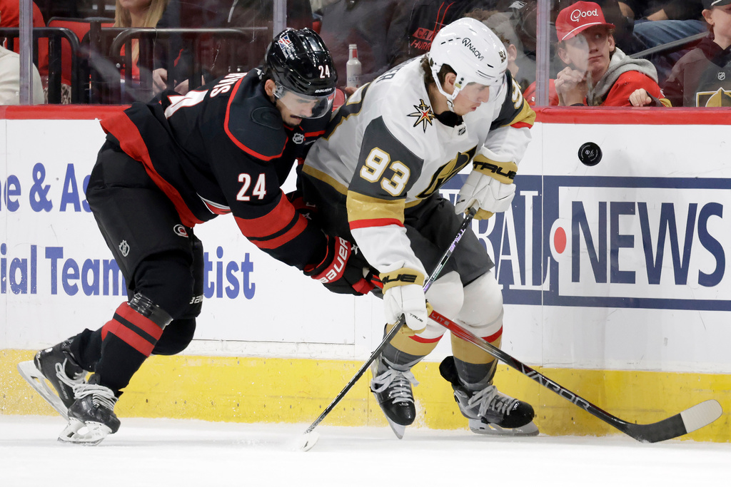 Carolina Hurricanes center Seth Jarvis (24) and Vegas Golden Knights right wing Mitch Marner (93) go for the puck during the first period of an NHL hockey game Tuesday, Oct. 28, 2025, in Raleigh, N.C. (AP Photo/Chris Seward)