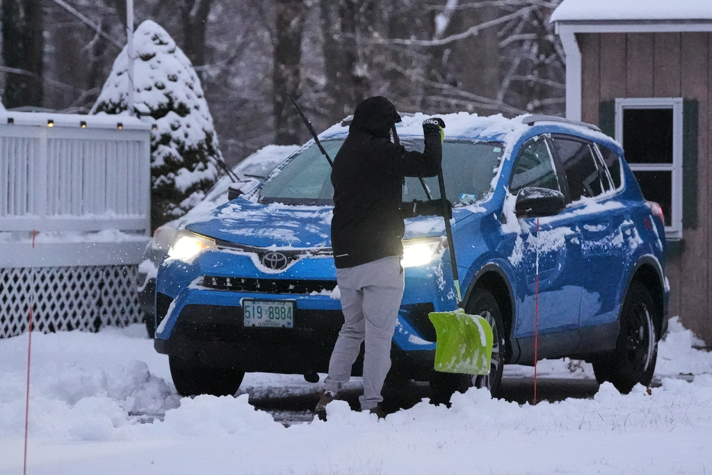 A man clears snow from his car during a winter storm, Tuesday, Dec. 2, 2025, in Salem, N.H. (AP Photo/Charles Krupa)