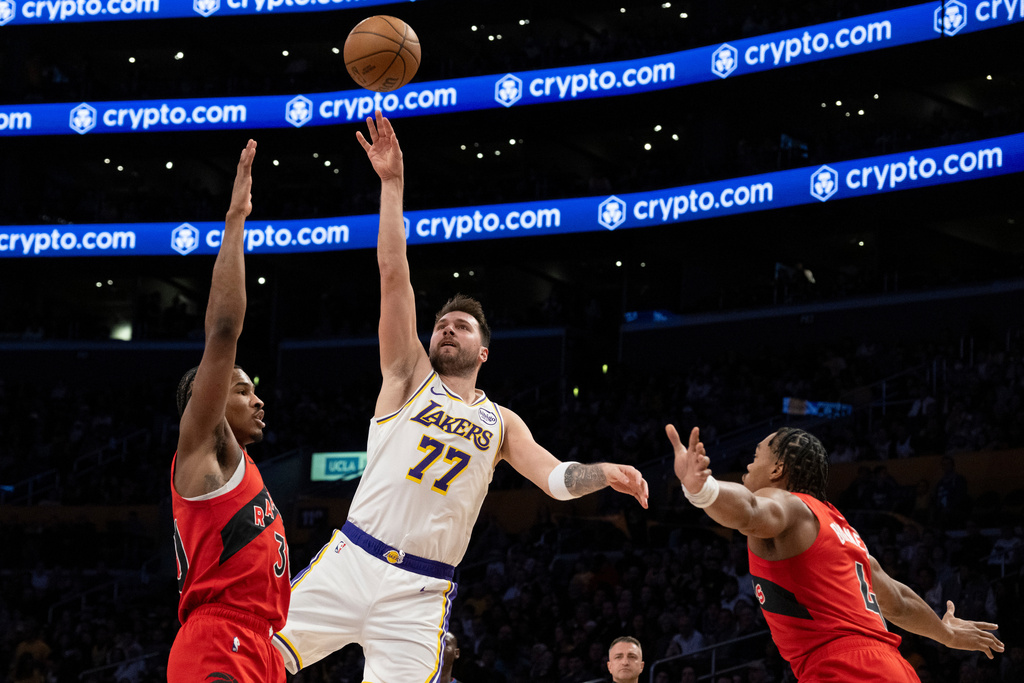 Los Angeles Lakers guard Luka Doncic (77) shoots over Toronto Raptors guard Ochai Agbaji (30) during the first half of an NBA basketball game in Los Angeles, Sunday, Jan. 18, 2026. (AP Photo/Kyusung Gong)